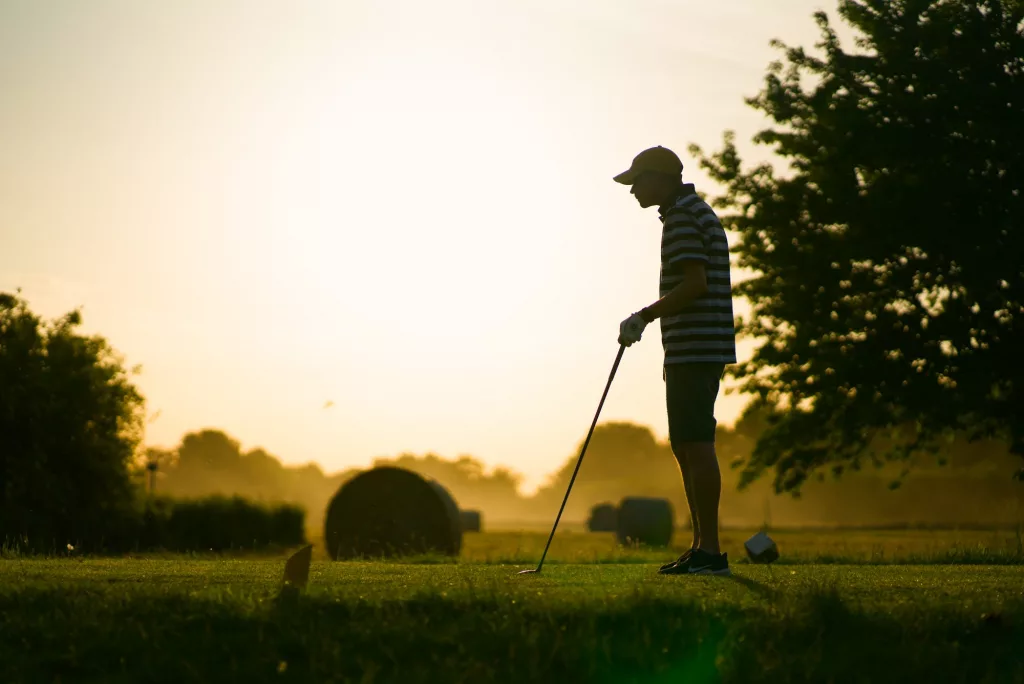 Golfer-Silhouette beim Abschlag im Abendlicht
