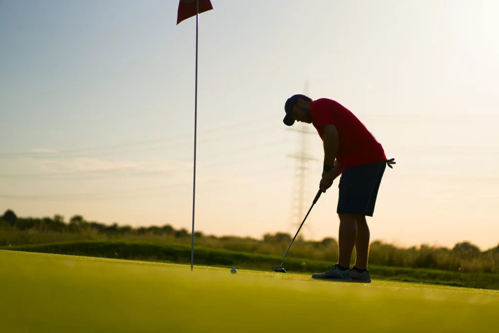 Golfer beim Putten in der Abendsonne