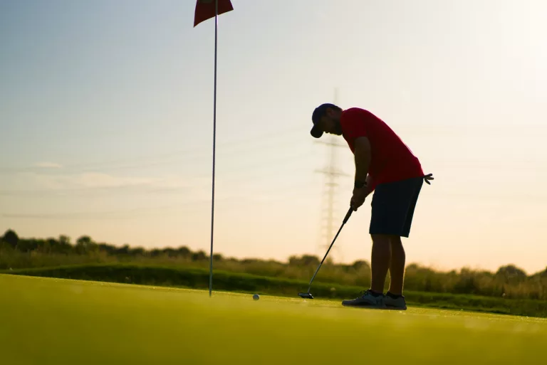 Golfer beim Putten in der Abendsonne
